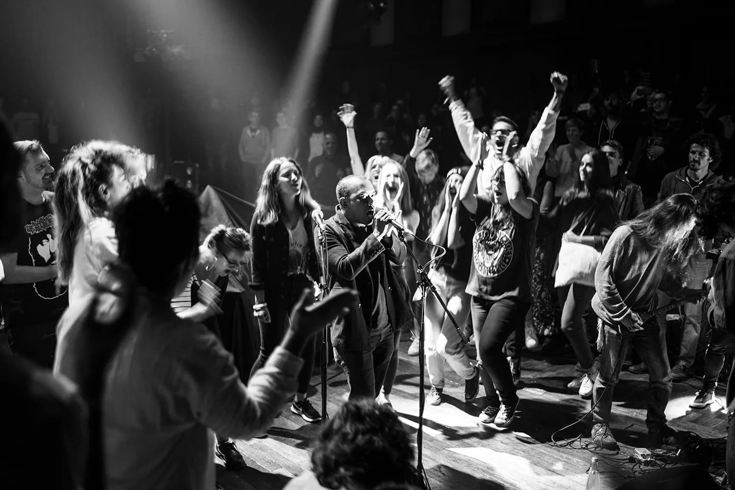 Singer and audience in shared chorus, hands raised