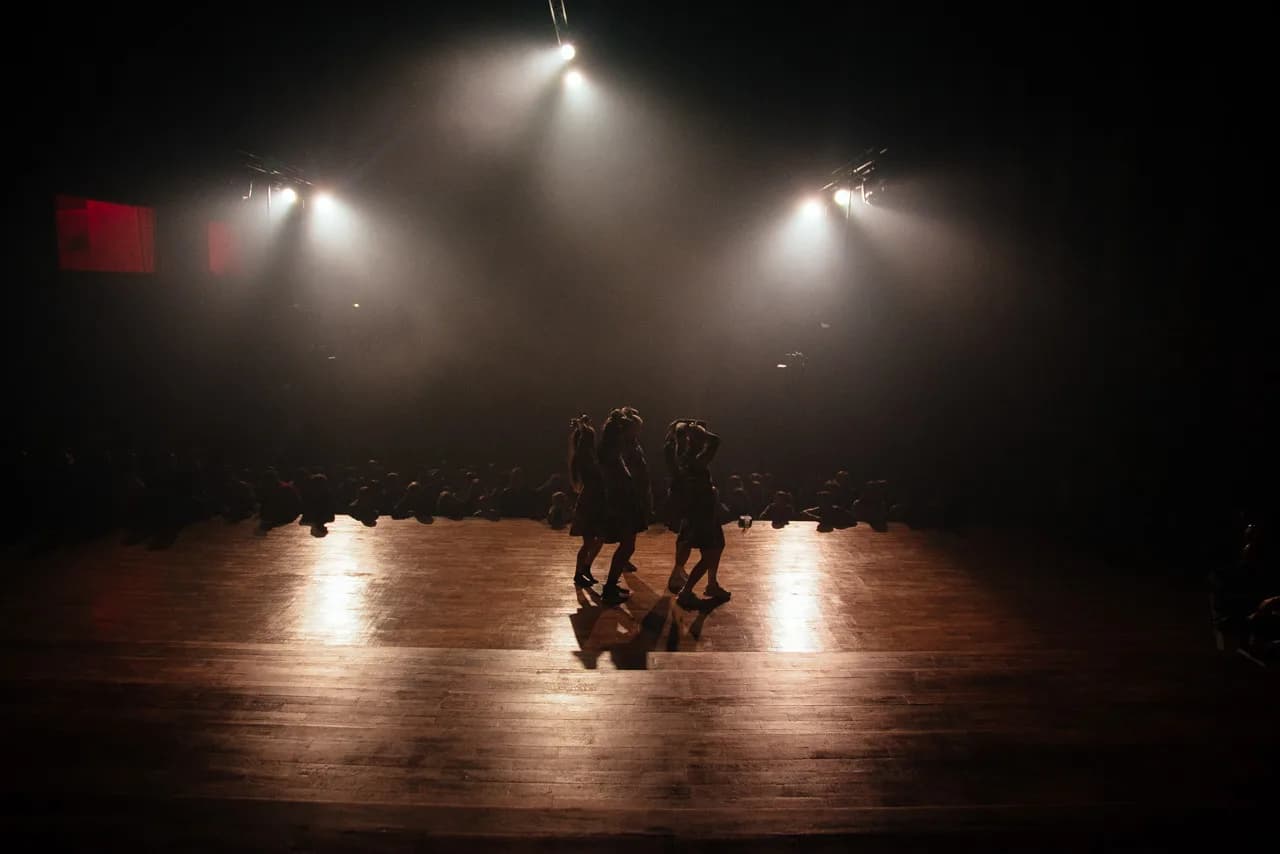 Dancers silhouetted on stage under spotlights